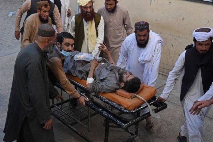 Orang-orang mendorong tandu yang membawa korban terluka dalam ledakan bom selama unjuk rasa pro-Palestina, di mana 6 orang tewas dan 14 lainnya luka-luka, di Chaman provinsi Balochistan Pakistan pada Jumat (21/5/2021). (AFP/KC)