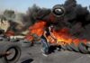 Seorang demonstran Palestina melempar ban yang terbakar ke tumpukan selama bentrokan dengan pasukan Israel di dekat pemukiman Yahudi Beit El dekat Ramallah di Tepi Barat pada 14 Mei 2021. (ABBAS MOMANI / AFP)