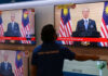 Seorang pria menonton televisi saat Perdana Menteri Malaysia Muhyiddin Yassin mengumumkan pengunduran dirinya saat ia berpidato di Kuala Lumpur pada 16 Agustus 2021 yang disiarkan langsung. (Foto: AFP/Arif Kartono via CNA)