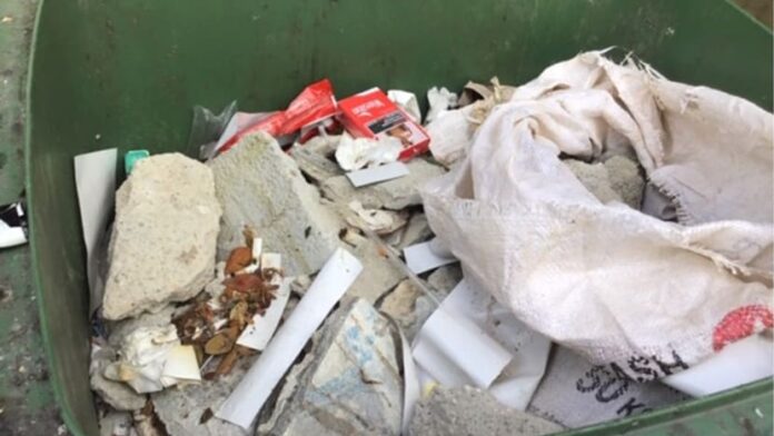 Kantong goni berisi beton dan ubin yang diretas dibuang secara ilegal di dalam tempat sampah umum milik penghuni di Jalan Besar. (Foto: NEA)