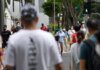 Pejalan kaki bermasker menyeberang jalan di Singapura. Kasus Covid-19 di Singapura sedang melonjak, mayoritas kasus lokal dan berada dalam komunitas. (Foto: Channel News Asia/Calvin Oh)
