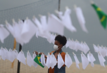 Seorang anggota LSM Rio de Paz meletakkan sapu tangan putih yang melambangkan perpisahan, untuk memberi penghormatan kepada 600.000 kematian akibat penyakit virus corona (Covid-19) di Brasil [Pilar Olivares/Reuters via Al Jazeera]