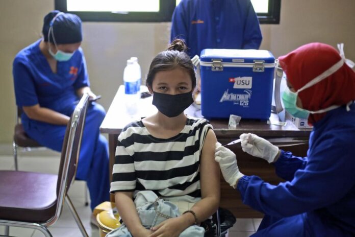 Seorang wanita menerima vaksin Covid-19 di Rumah Sakit Universitas Sumatera Utara di Medan, Sumatera Utara, Indonesia, 26 November 2021. (Foto: AP Photo/Binsar Bakkara via hrw.org)