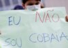 Seorang anak memegang poster bertuliskan 'Saya bukan kelinci percobaan' saat demonstrasi menentang paspor Covid dan vaksinasi wajib untuk anak-anak. (Foto: Ueslei Marcelino/Reuters via Guardian)