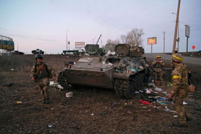 Foto Tentara Ukraina terlihat di samping kendaraan lapis baja yang hancur, yang menurut mereka milik tentara Rusia, di luar Kharkiv, Ukraina, Kamis (24/2/2022).(MAKSIM LEVIN/ANTARA FOTO/REUTERS)
