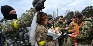 Prajurit pertahanan teritorial Ukraina, Valery (3rdL) dan Lesya (2ndL), menikah tidak jauh dari pos pemeriksaan di pinggiran Kyiv pada 6 Maret 2022. (Photo by Genya SAVILOV / AFP) (AFP/GENYA SAVILOV)