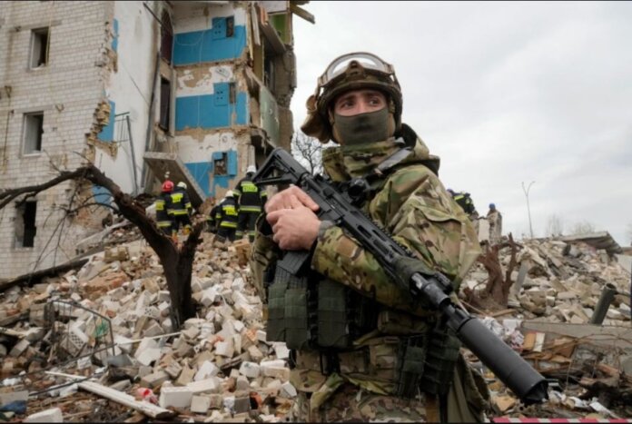 Tentara Ukraina berdiri di dekat apartemen yang hancur di Borodyanka, Ukraina, Rabu, 6 April 2022. (Efrem Lukatsky/AP via Al Jazeera)