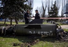 Polisi Ukraina memeriksa puing roket, bertuliskan 'Untuk anak-anak kita' dalam bahasa Rusia, yang jatuh di area gedung utama stasiun Kramatorsk usai terjadi serangan (AFP/FADEL SENNA)