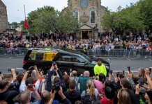 Puluhan ribu pelayat yang berbaris di sepanjang rute, banyak dalam keheningan saat menyaksikan mobil yang membawa jenazah Ratu Elizabeth. Jamie Williamson/Pool via REUTERS